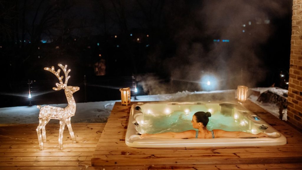 Frau in Outdoor Whirlpool mit Weihnachtsdekoration im Winter draußen