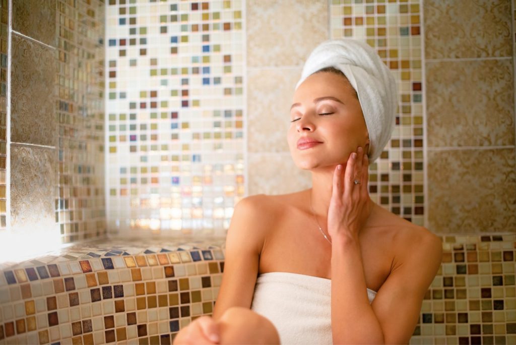 Eine Frau sitzt in einem Saunabereich.