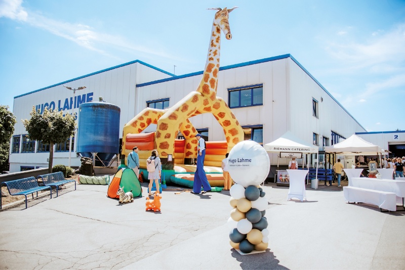Eine Jubiläumsfeier für das Team von Hugo Lahme. Zu sehen ist eine Hüpfburg für Kinder und ein Clown auf Stelzen.