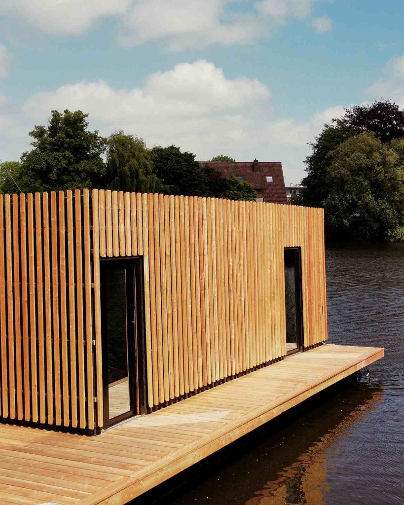 Zu sehen ist die Ahoi-Sauna, die auf einem Floss im Wasser liegt.