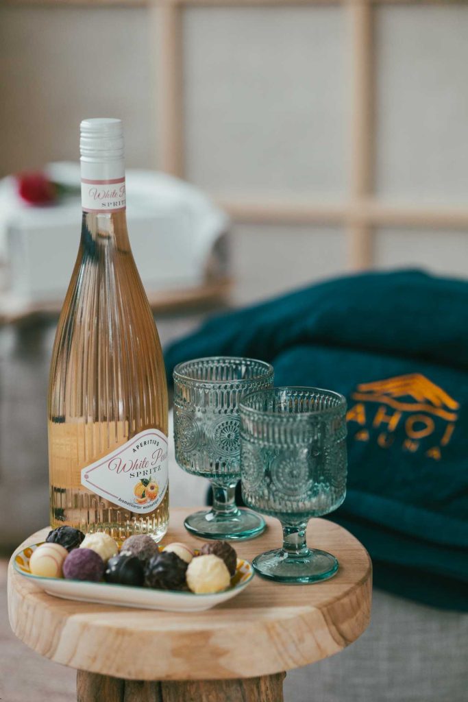 Ein Detailbild der Verpflegung. Eine Flasche Wein, zwei Gläser und Pralinen sind z sehen.