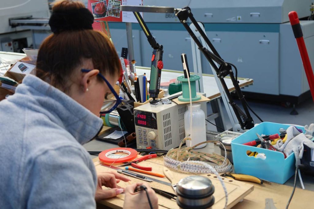 Ein Mitarbeiterin beugt sich über die Platine, die sie bearbeitet.