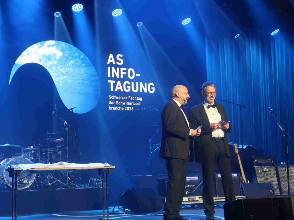 Die beiden Geschäftsführer Domenico Conte und Yves Burgener im schwarzen Anzug mit Fliege auf der Bühne bei der As Infotagung.