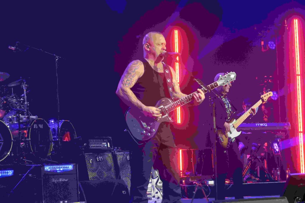 Die Rockband liefert eine Show auf der Bühne und das Publikum feiert.