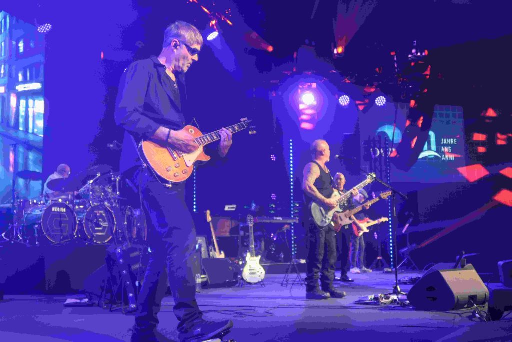 Die Rockband liefert eine Show auf der Bühne und das Publikum feiert.