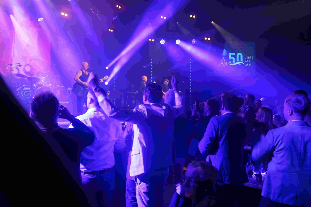 Die Rockband liefert eine Show auf der Bühne und das Publikum feiert.