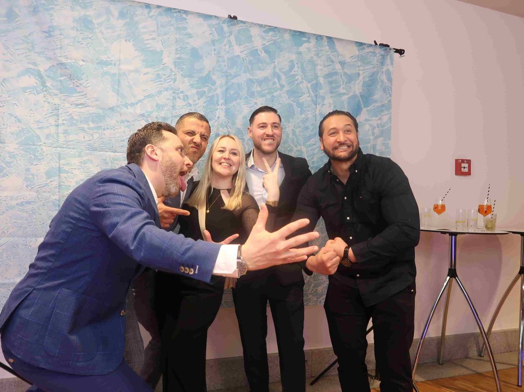 Eine Frau und vier Männer machen ein Gruppenbild mit lustigen Posen.