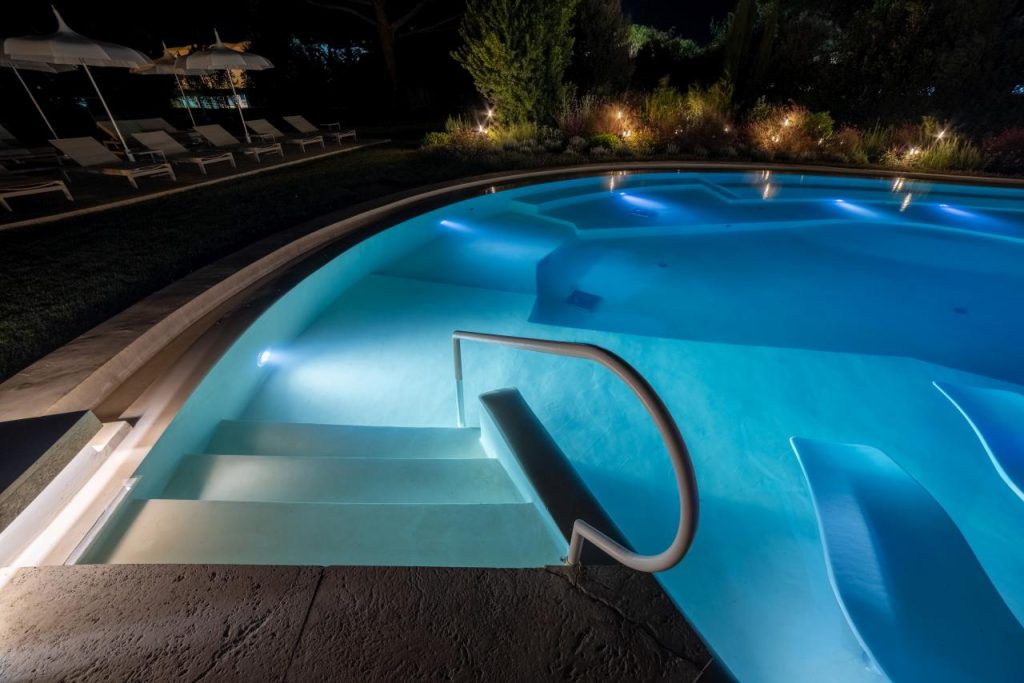 Zu sehen ist der beleuchtete Einstieg eines Pools in der Dunkelheit.