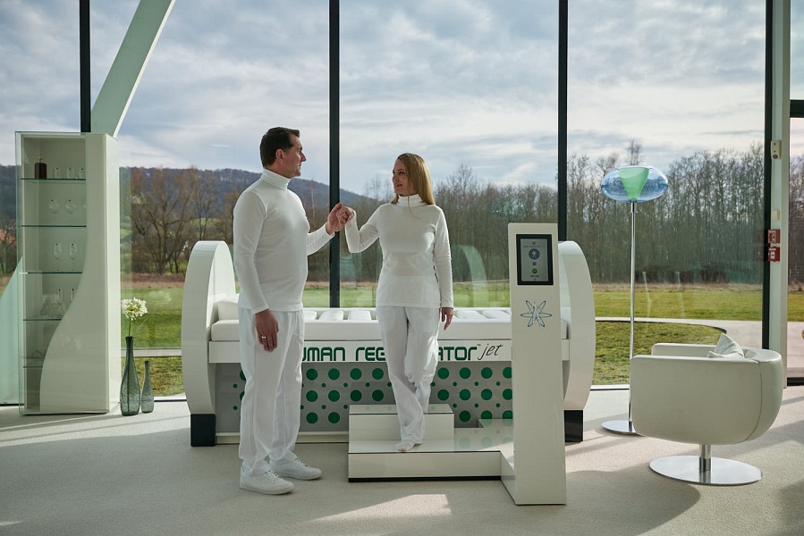 Ein Mann hilft einer Frau aus einer runden Kabine auszusteigen.