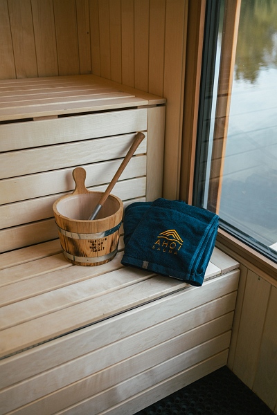 Ein Eimer mit Schöpfkelle und ein Handtuch liegen auf der Saunaliege.